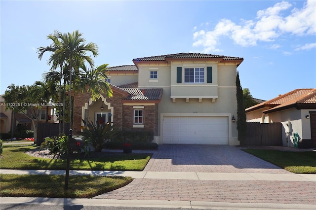 mediterranean / spanish-style home with a garage, a tile roof, fence, decorative driveway, and stucco siding