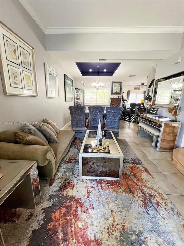 living room with a chandelier, a tray ceiling, crown molding, and tile patterned floors