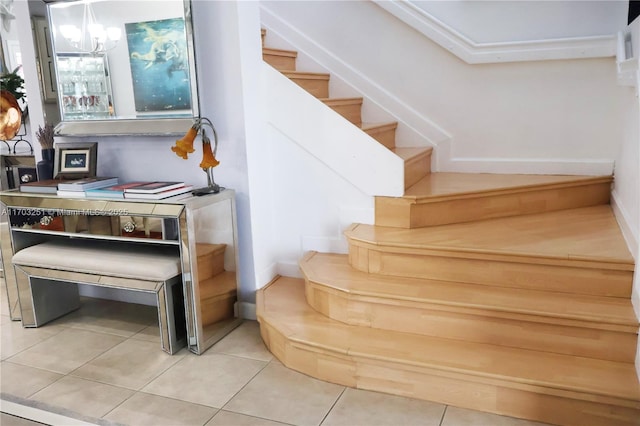 stairs with tile patterned flooring and an inviting chandelier