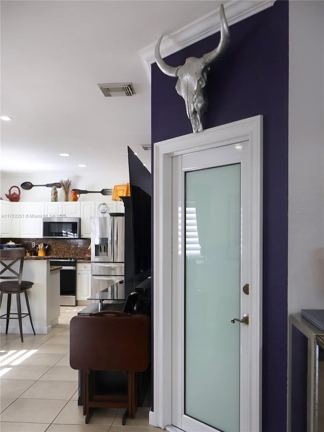 interior space featuring white cabinetry, visible vents, appliances with stainless steel finishes, decorative backsplash, and dark countertops