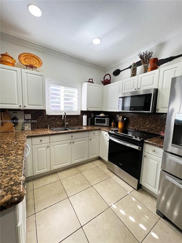 kitchen with light tile patterned floors, stainless steel appliances, tasteful backsplash, ornamental molding, and a sink