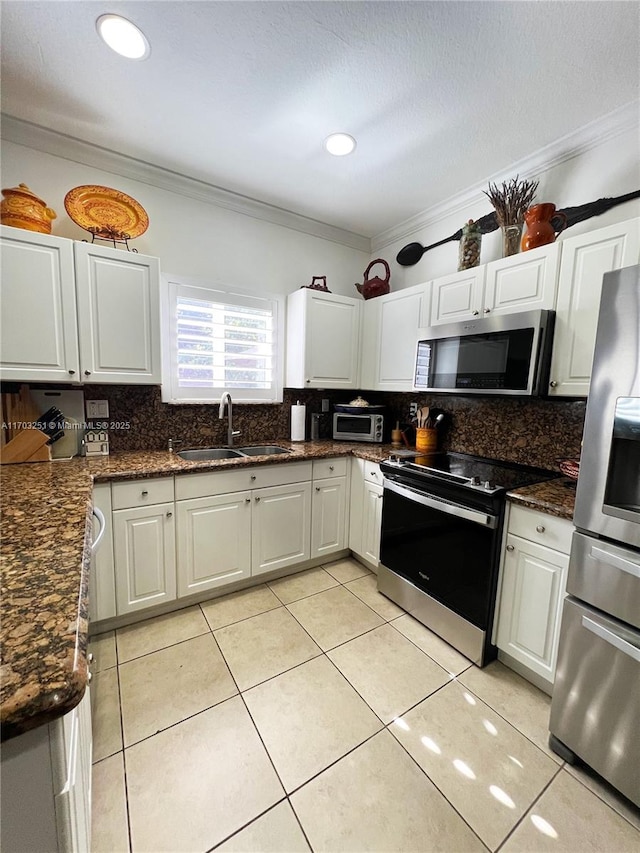 kitchen featuring stainless steel appliances, a sink, backsplash, white cabinetry, and crown molding