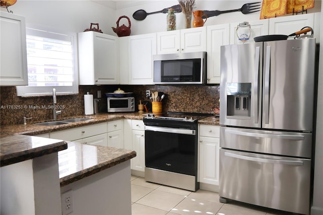 kitchen with white cabinets, a sink, decorative backsplash, appliances with stainless steel finishes, and light tile patterned floors