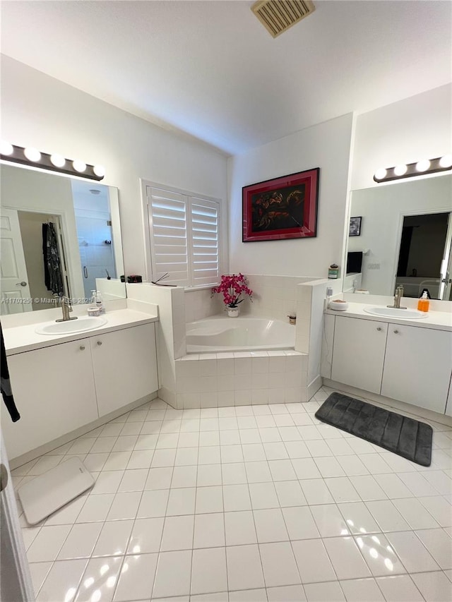 bathroom with tile patterned flooring, two vanities, a sink, visible vents, and a bath