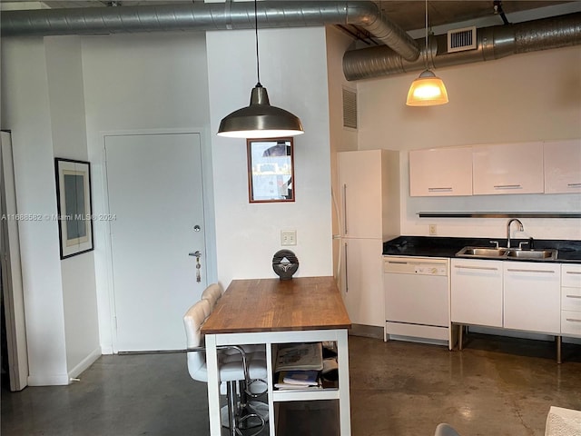 kitchen featuring sink, hanging light fixtures, white dishwasher, a towering ceiling, and white cabinets