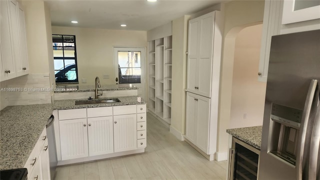 kitchen with light stone countertops, sink, white cabinets, and stainless steel appliances