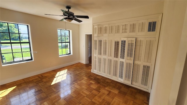 unfurnished bedroom featuring dark parquet flooring, ceiling fan, and a closet