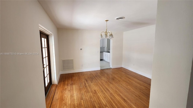 unfurnished room featuring hardwood / wood-style flooring and an inviting chandelier