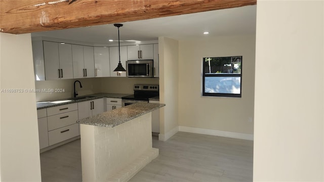 kitchen featuring sink, hanging light fixtures, stainless steel appliances, dark stone countertops, and light hardwood / wood-style floors