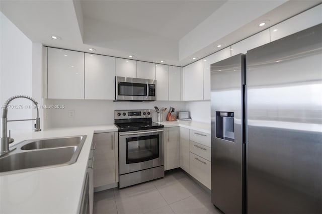 kitchen with sink, white cabinets, light tile patterned floors, and appliances with stainless steel finishes