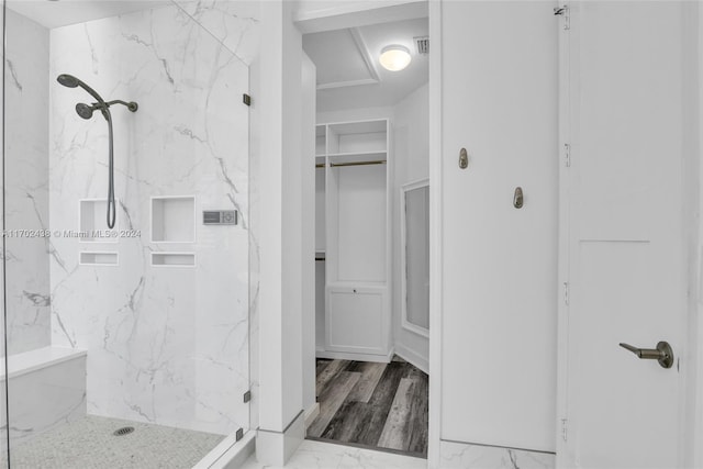 bathroom with a tile shower and hardwood / wood-style flooring