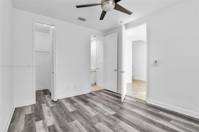 unfurnished bedroom featuring a spacious closet, a closet, and ceiling fan