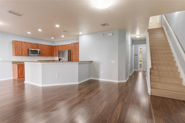 kitchen with backsplash, light stone counters, a textured ceiling, stainless steel appliances, and dark hardwood / wood-style floors