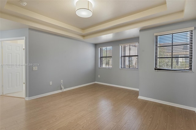 unfurnished room featuring a tray ceiling and light hardwood / wood-style flooring