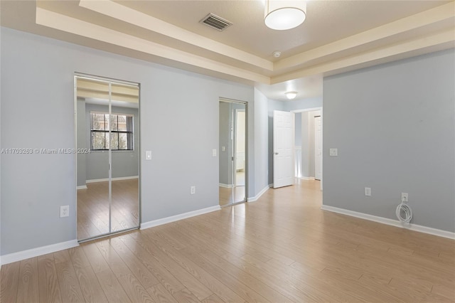 unfurnished room with light hardwood / wood-style floors and a raised ceiling