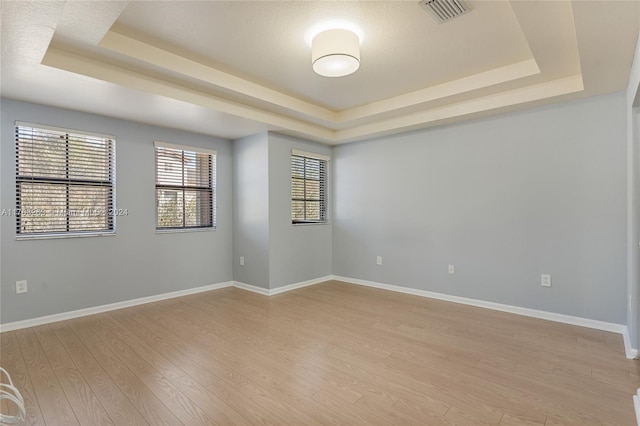 spare room featuring light hardwood / wood-style flooring and a tray ceiling