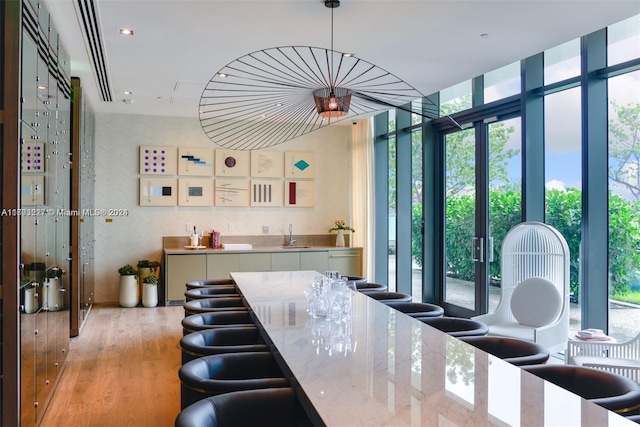 kitchen featuring light wood-type flooring, white cabinetry, hanging light fixtures, and a healthy amount of sunlight