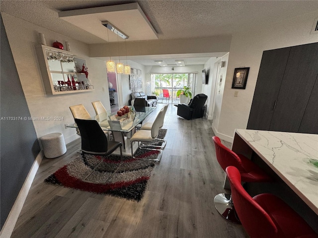 dining space with hardwood / wood-style floors and a textured ceiling