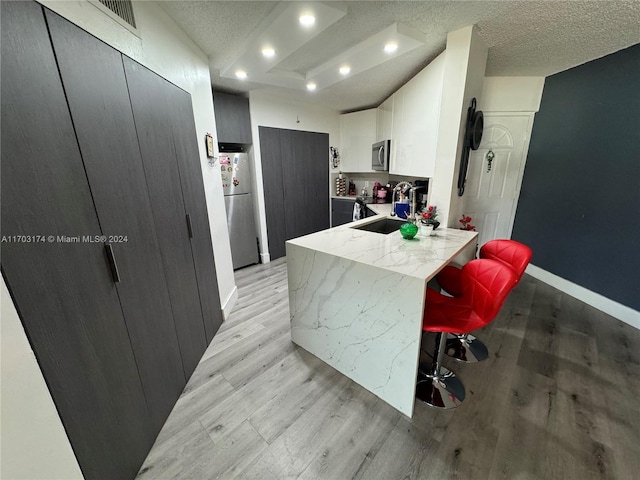 kitchen featuring a kitchen bar, white cabinetry, appliances with stainless steel finishes, and light hardwood / wood-style flooring