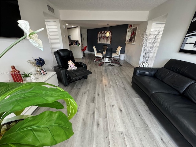 living room with a textured ceiling and light wood-type flooring