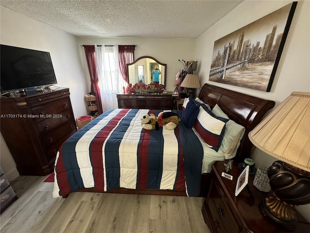 bedroom with light hardwood / wood-style floors and a textured ceiling