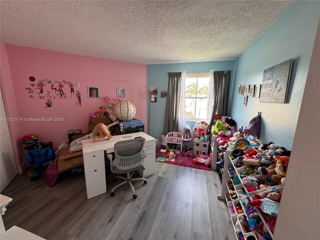 home office with light hardwood / wood-style floors and a textured ceiling