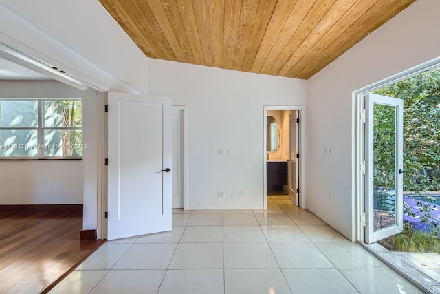 unfurnished bedroom featuring light tile patterned floors, ensuite bathroom, vaulted ceiling, and wood ceiling