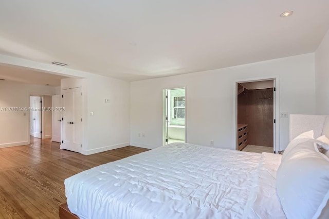 bedroom with hardwood / wood-style floors and ensuite bath