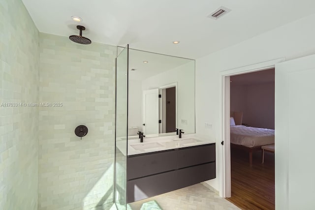 bathroom featuring hardwood / wood-style floors, vanity, and tiled shower