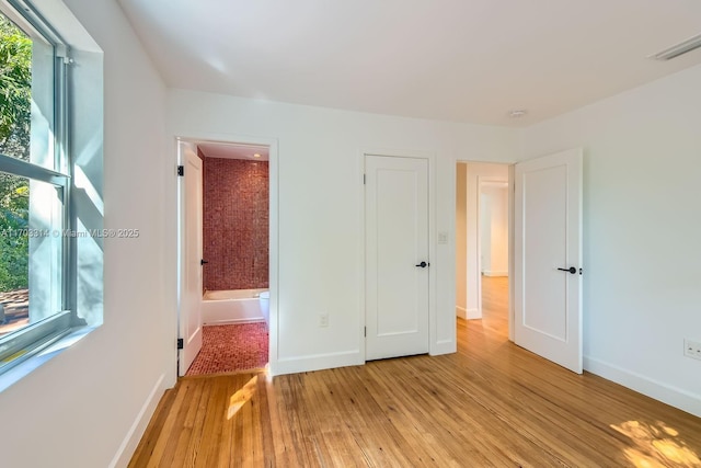 unfurnished bedroom featuring light wood-type flooring and ensuite bath