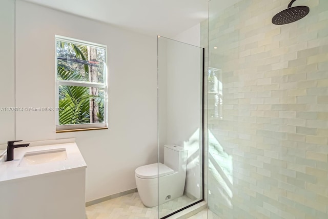 bathroom with toilet, a tile shower, and vanity