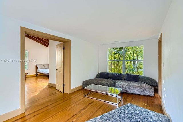 living room featuring lofted ceiling with beams and wood-type flooring