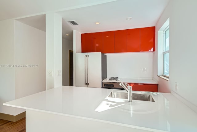 kitchen featuring kitchen peninsula, high quality fridge, sink, and hardwood / wood-style flooring