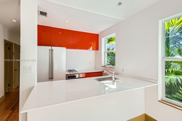 kitchen with sink, dark hardwood / wood-style floors, high quality fridge, wall oven, and kitchen peninsula