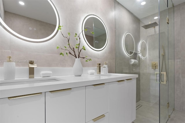 bathroom with a shower with door, vanity, and tile walls