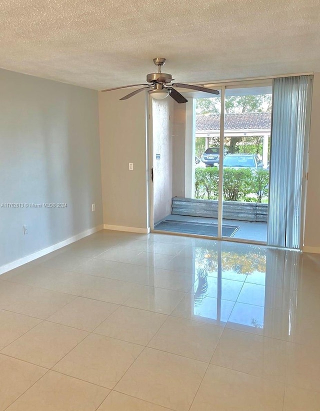 tiled empty room featuring ceiling fan and a textured ceiling