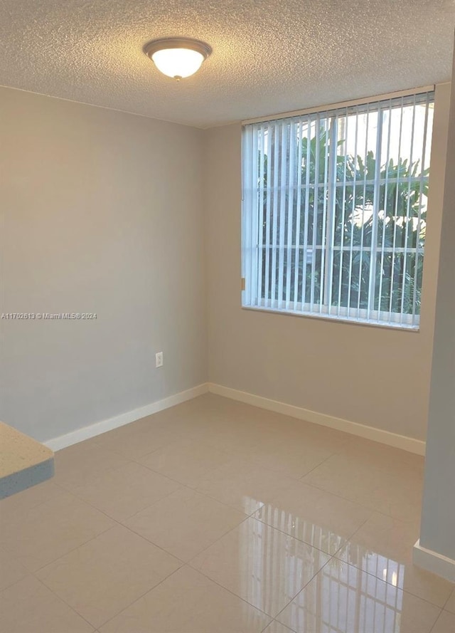 spare room featuring tile patterned flooring and a textured ceiling