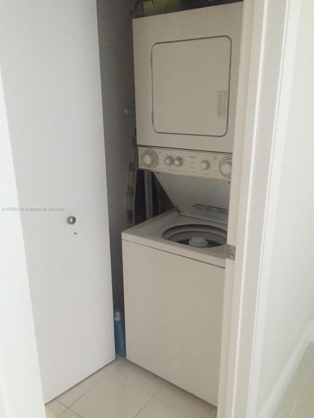 laundry room featuring light tile patterned floors and stacked washer and clothes dryer