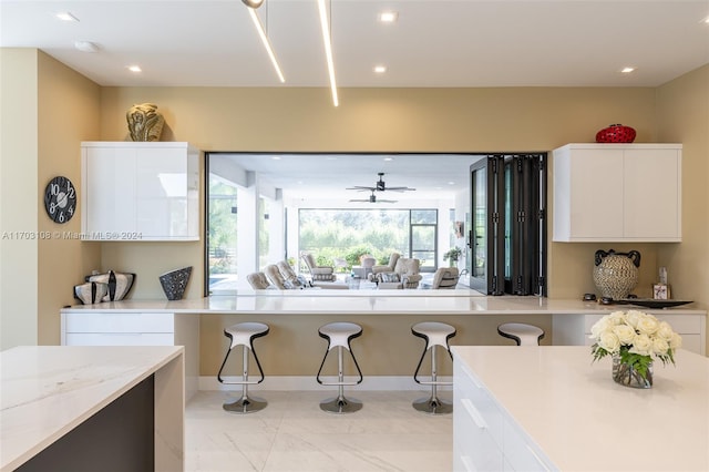1410 Shadow Meadow Ln, Deland, FL 32724 - kitchen with white cabinets, a kitchen breakfast bar, modern cabinets, light marble finish floors, and recessed lighting