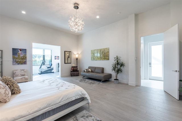 bedroom featuring access to outside, light hardwood / wood-style flooring, and an inviting chandelier