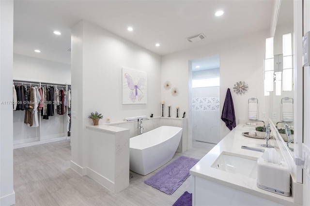 1410 Shadow Meadow Ln, Deland, FL 32724 - bathroom featuring a freestanding bath, double vanity, wood finished floors, recessed lighting, and a spacious closet