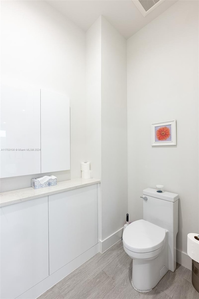 bathroom featuring toilet, vanity, and hardwood / wood-style flooring