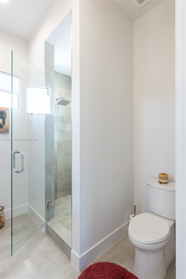 bathroom with tile patterned flooring, a shower with shower door, and toilet