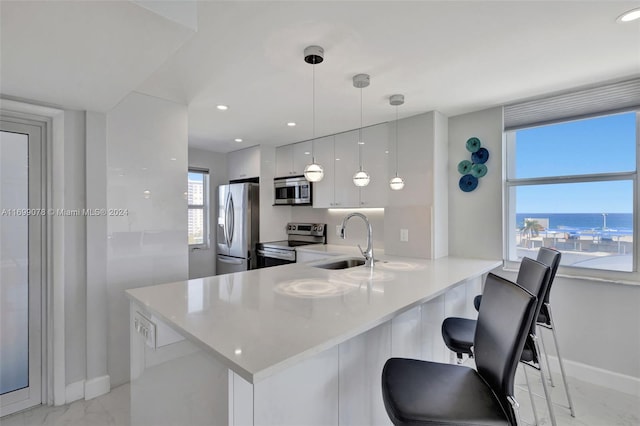 kitchen with white cabinetry, sink, kitchen peninsula, pendant lighting, and appliances with stainless steel finishes