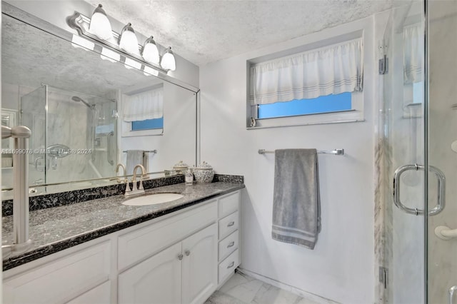 bathroom with vanity, a shower with shower door, and a textured ceiling