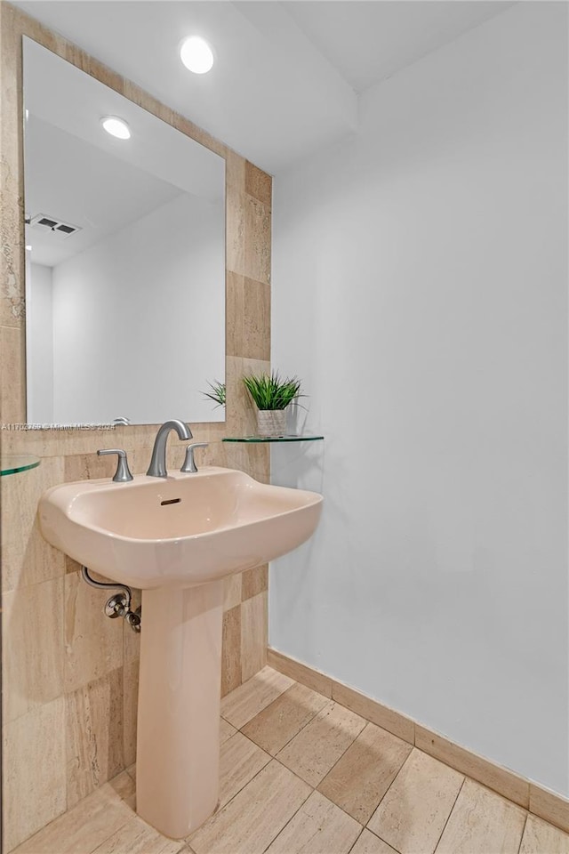 bathroom featuring tile walls and sink