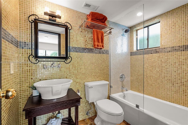 full bathroom featuring tiled shower / bath, toilet, tile walls, and sink