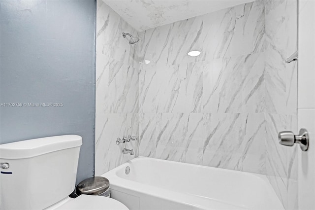 bathroom featuring toilet and tiled shower / bath