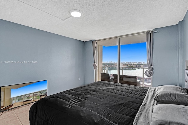 tiled bedroom featuring floor to ceiling windows, a textured ceiling, and a water view