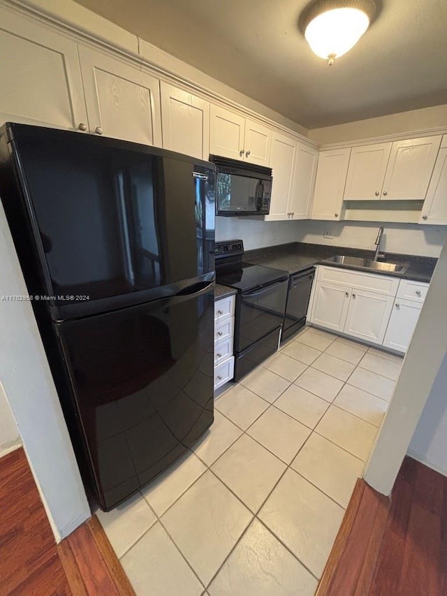 kitchen with black appliances, light tile patterned flooring, white cabinets, and sink